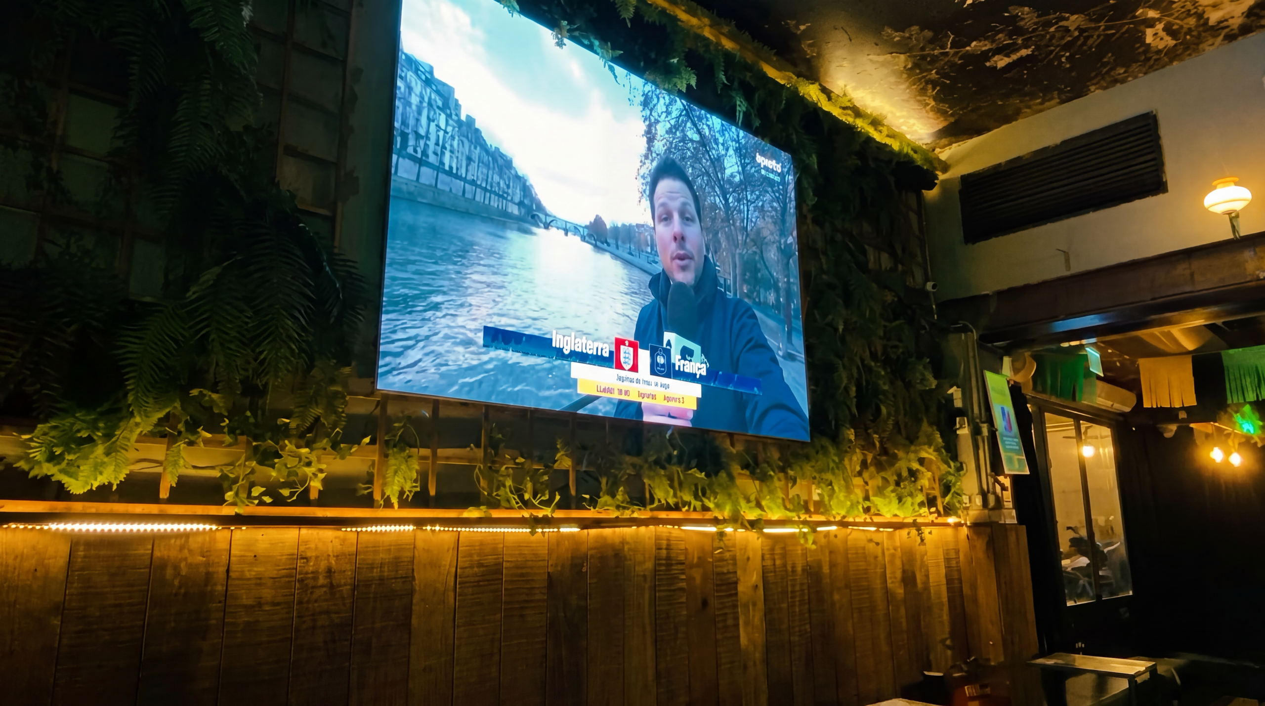 Painel de LED integrado à parede verde do Bar Aurora