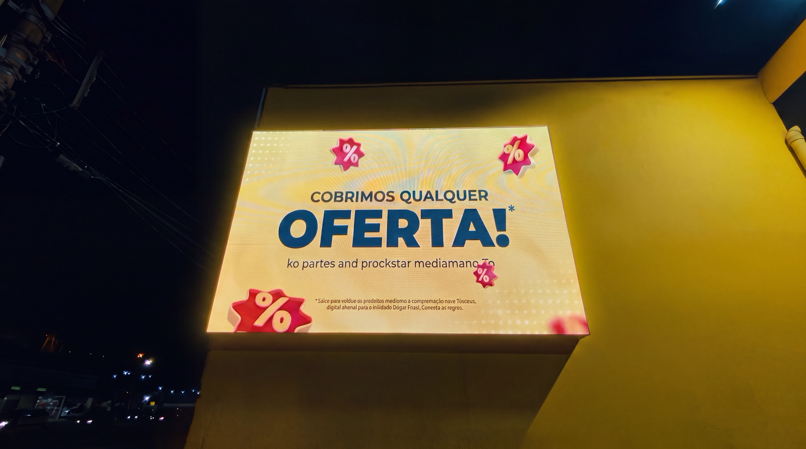 Painel exibindo Cobrimos Qualquer Oferta aceso à noite